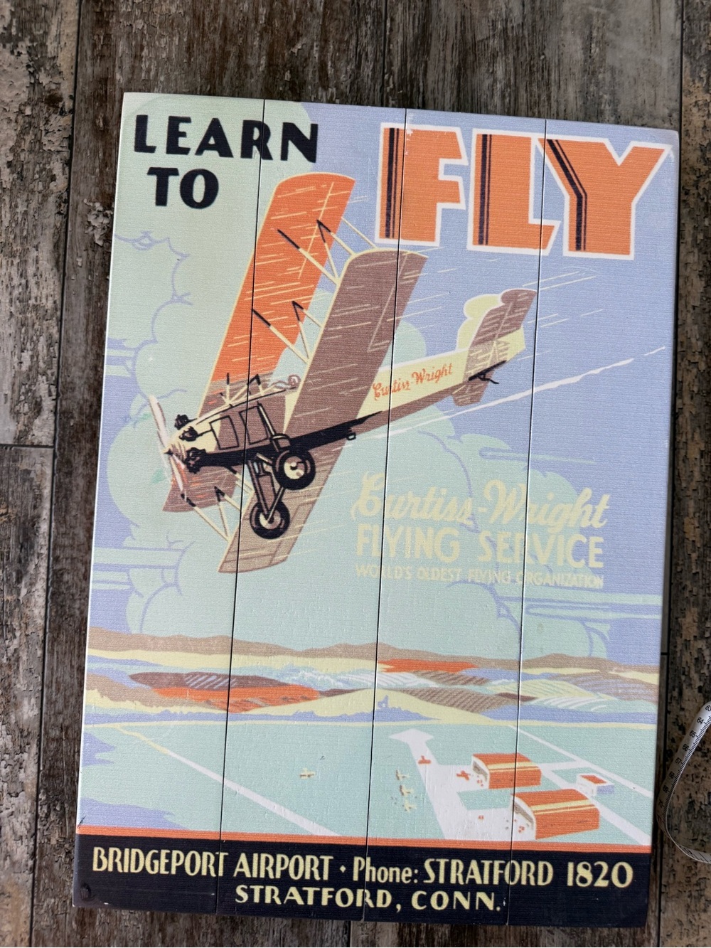 Wood panel reproduction of a 1930s Curtiss-Wright Flying Service travel poster